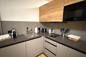 A modern kitchen with a built-in oven, a coffee maker, a kettle, and a sink. - Timber Studio Schladming - Alpine Corner (Schladming)