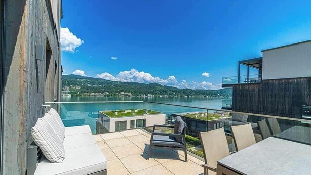 Terraço no telhado com piscina, área de estar externa e vista para um lago e montanhas.