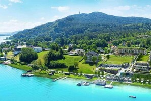 A coastal town with buildings, a marina, and a hill in the background. - Hermitage Apartment A09 - Lake view & access (Maria Wörth)