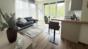 Uma sala de estar moderna com sofá, mesa de centro e área de jantar com cadeiras e bancada de cozinha.