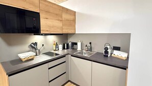 Una cocina moderna con microondas, tostadora y tetera sobre la encimera, y un lavabo con grifo.