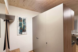 A room with a wooden ceiling, a wardrobe, and a painting on the wall.