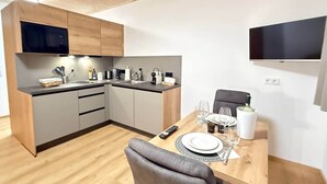 Una cocina moderna con armarios grises, encimera de madera y comedor con mesa para dos.