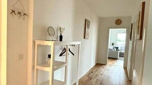 Un pasillo con una consola blanca, un perchero colgante y una alfombra estampada.