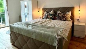 Un dormitorio con una cama grande, un armario, una mesita de noche y una lámpara colgante.