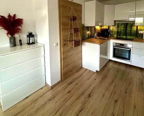 Eine moderne Küche mit weißen Schränken, Holzboden und einer hängenden Korbkorb.