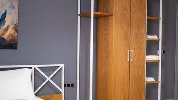 Un dormitorio con una cama, un armario de madera con estantes y un cuadro en la pared.