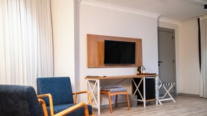 A room with a desk, a chair, a television mounted on the wall, and a door. - Mec Avila (Amasya)