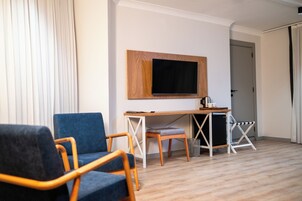 Una habitación con escritorio, silla, televisor en la pared y una puerta.