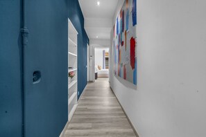 A hallway with a blue door, white shelves, and a colorful abstract painting on the wall. - "Casa Brera" Penthouse for 8 people + Duomo 5 min (Milano)