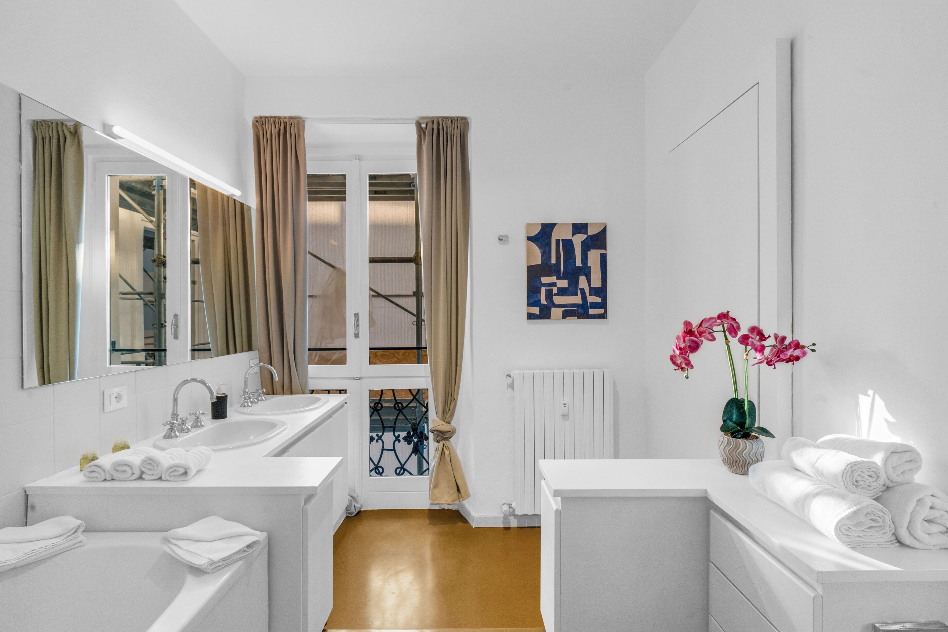 Un baño moderno con dos lavamanos, un espejo, una ducha y una orquídea en maceta.