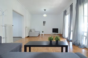 A modern living room with a sofa, a coffee table, a TV, and a radiator. - Spacious minimal apartment at Chalandri (Chalandri)