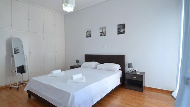 Ein Schlafzimmer mit Bett, Nachttischen, Kommode, Spiegel und Wandbildern.