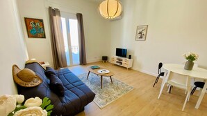 A modern living room with a sofa, coffee table, TV, and dining area. - "Keia" Pedestrianized city center, Air conditioning, Wifi (Sète)