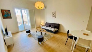 A living room with a sofa, a coffee table, a dining table, and a TV on a stand. - "Keia" Pedestrianized city center, Air conditioning, Wifi (Sète)
