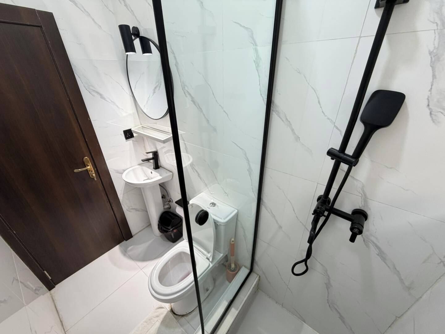Une salle de bain comprenant des toilettes, un lavabo et un espace douche.