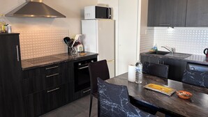 Una cocina moderna con armarios oscuros, una campana extractora de acero inoxidable, un microondas y un refrigerador.