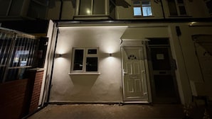 A two-story house with a front door, a small window, and a garage door.