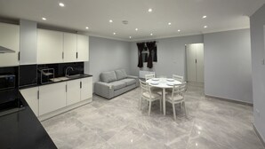 A modern kitchen with white cabinets, a black countertop, and a dining area with a round table and chairs.
