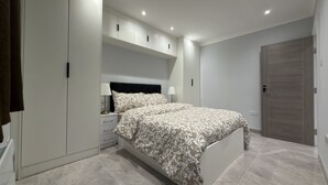 A bedroom with a bed, nightstands, a wardrobe, and a door.