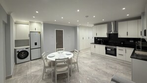 A modern kitchen with white cabinetry, a built-in oven, and a dining area with a round table and chairs.