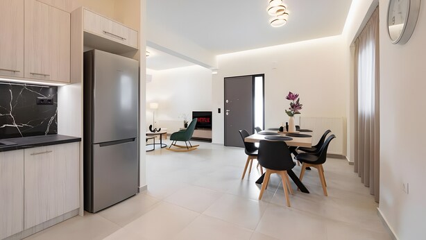 A modern kitchen with a built-in refrigerator, dining area with a table and chairs, and a TV in the background. - Apartment 'Zoelgrek Luxury Suite 1' with Private Terrace, Wi-Fi and Air Conditioning (Iraklio)