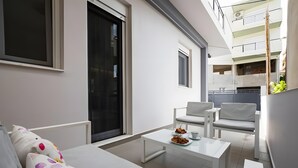 A modern living room with a sofa, two white armchairs, a coffee table, and a dining table with a plate of food. - Apartment 'Zoelgrek Luxury Suite 1' with Private Terrace, Wi-Fi and Air Conditioning (Iraklio)