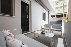 Una sala de estar moderna con un sofá, dos sillones blancos, una mesa de centro y una mesa de comedor con un plato de comida.