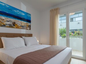 Ein Hotelzimmer mit Bett, großem Fenster und einem Gemälde an der Wand.