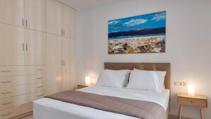 A bedroom with a bed, a nightstand, a wardrobe, and a painting on the wall. - Zoelgrek Luxury Suite 2 Apartment with Shared Terrace, Wi-Fi & Air Conditioning (Iraklio)