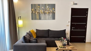 A living room with a sofa, a coffee table, a painting, and a door. - Zoelgrek Luxury Suite 2 Apartment with Shared Terrace, Wi-Fi & Air Conditioning (Iraklio)