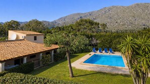 A pool with lounge chairs, a building with a tiled roof, and a mountainous backdrop. - Villa del la Vilar in Mallorca (Pollença)