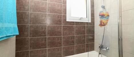 A bathroom with a bathtub, a shower, and a window.