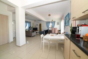 Uma sala de estar moderna com área de jantar, cozinha e uma porta visível que dá para outro cômodo.
