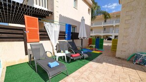A courtyard with outdoor seating, a pool, and a building with balconies. - Villa Chromata in Pernera (Paralimni)