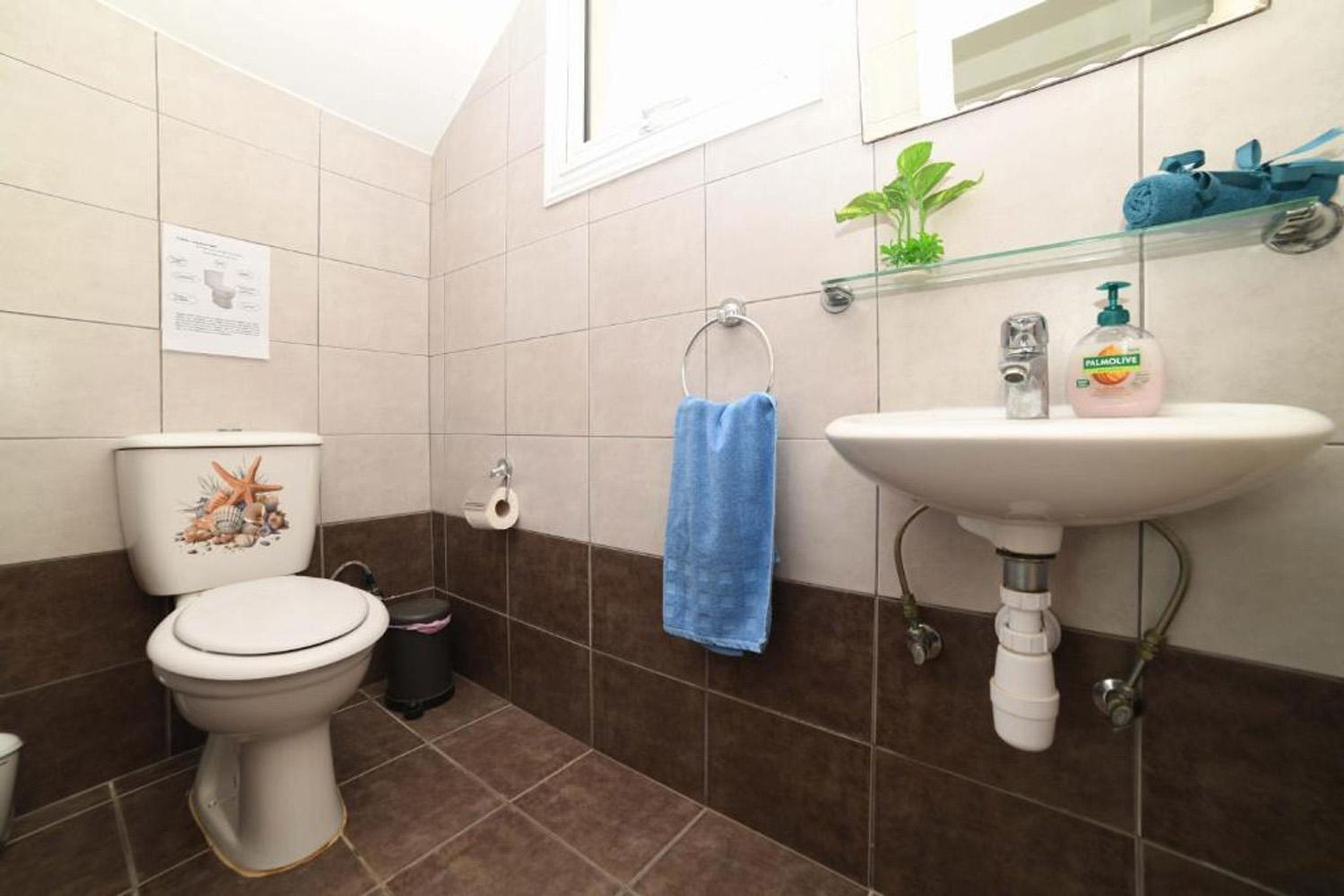 A bathroom with a toilet, sink, and a blue towel hanging on the wall.