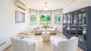 A modern living room with a sofa, chairs, a table, and a cabinet.
