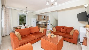 Ein Wohnzimmer mit zwei orangenen Sofas, einem Couchtisch und einem Fernseher.