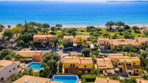 Vista aérea de una zona residencial costera con casas, una piscina y una playa.