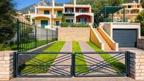 Un edificio de varios pisos con un muro de piedra, una entrada con portones y una escalera que conduce a los niveles superiores.