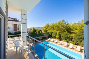 A balcony with a pool, lounge chairs, and a view of the landscape. - Four Seasons Villa in Oludeniz (Fethiye)