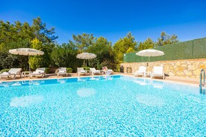 A clear blue pool with lounge chairs and umbrellas, surrounded by greenery and a stone wall. - Four Seasons Villa in Oludeniz (Fethiye)