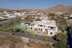A residential area with white buildings, a swimming pool, and a mountain in the background. - Villa Ballena Azul in Teguise (Teguise)