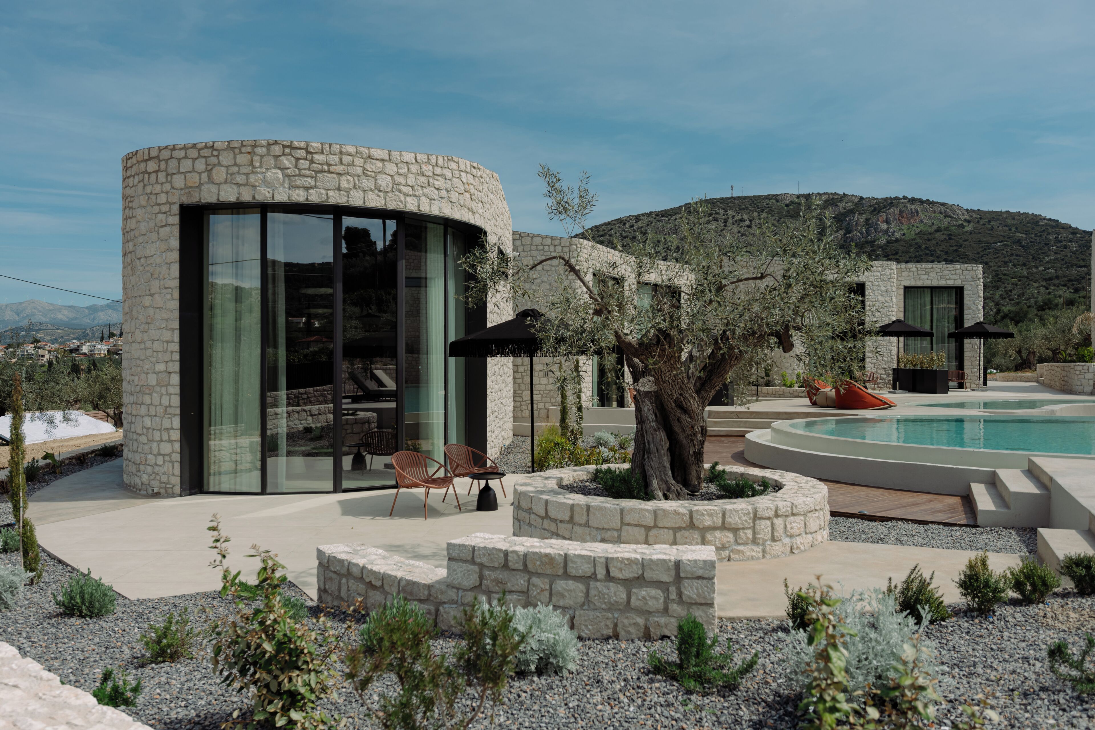 A modern house with a stone exterior, a swimming pool, and outdoor seating.
