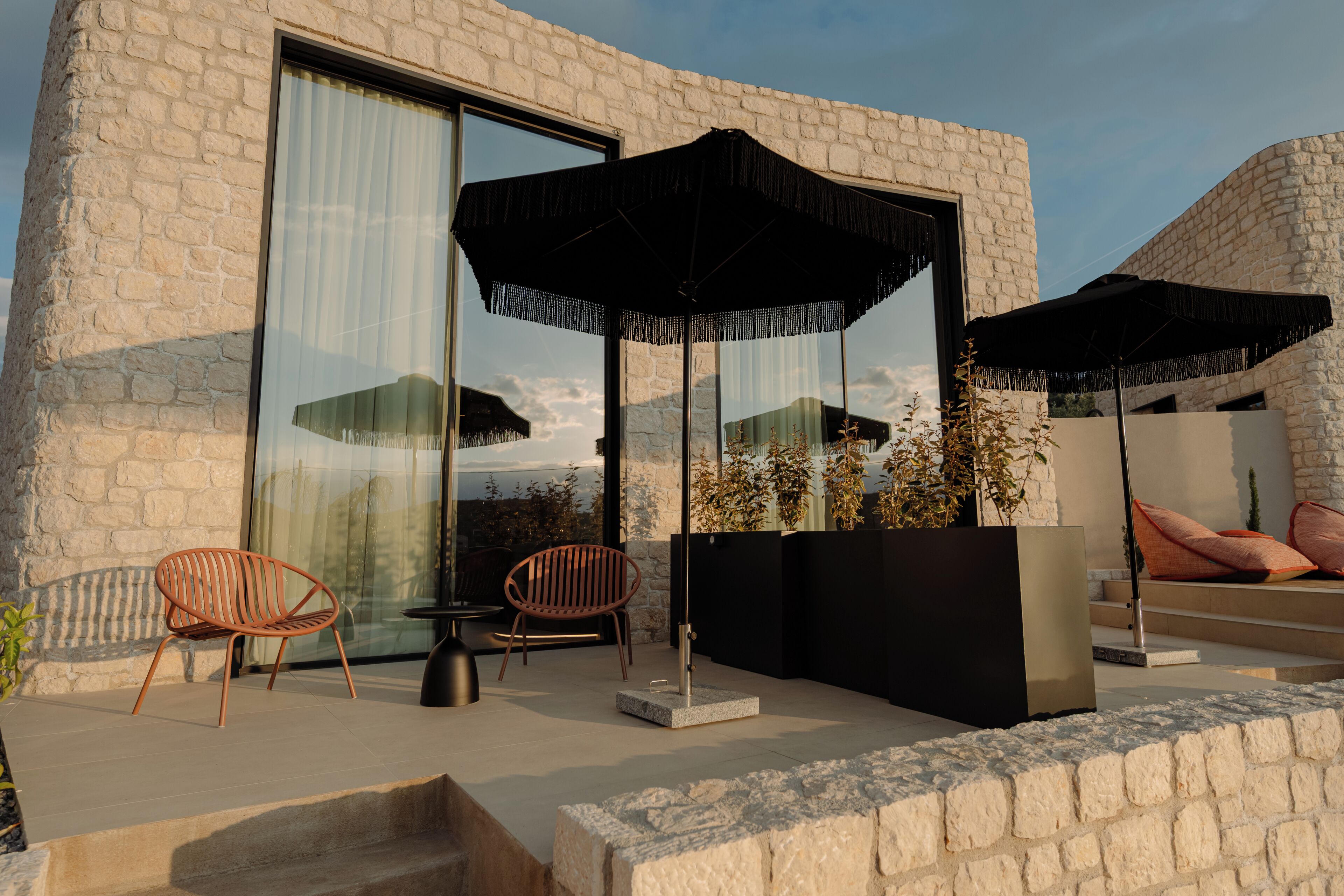 A modern outdoor seating area with two chairs, a table, and two large umbrellas.