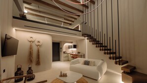 Un salon moderne avec un canapé blanc, une table basse, un téléviseur et un escalier.