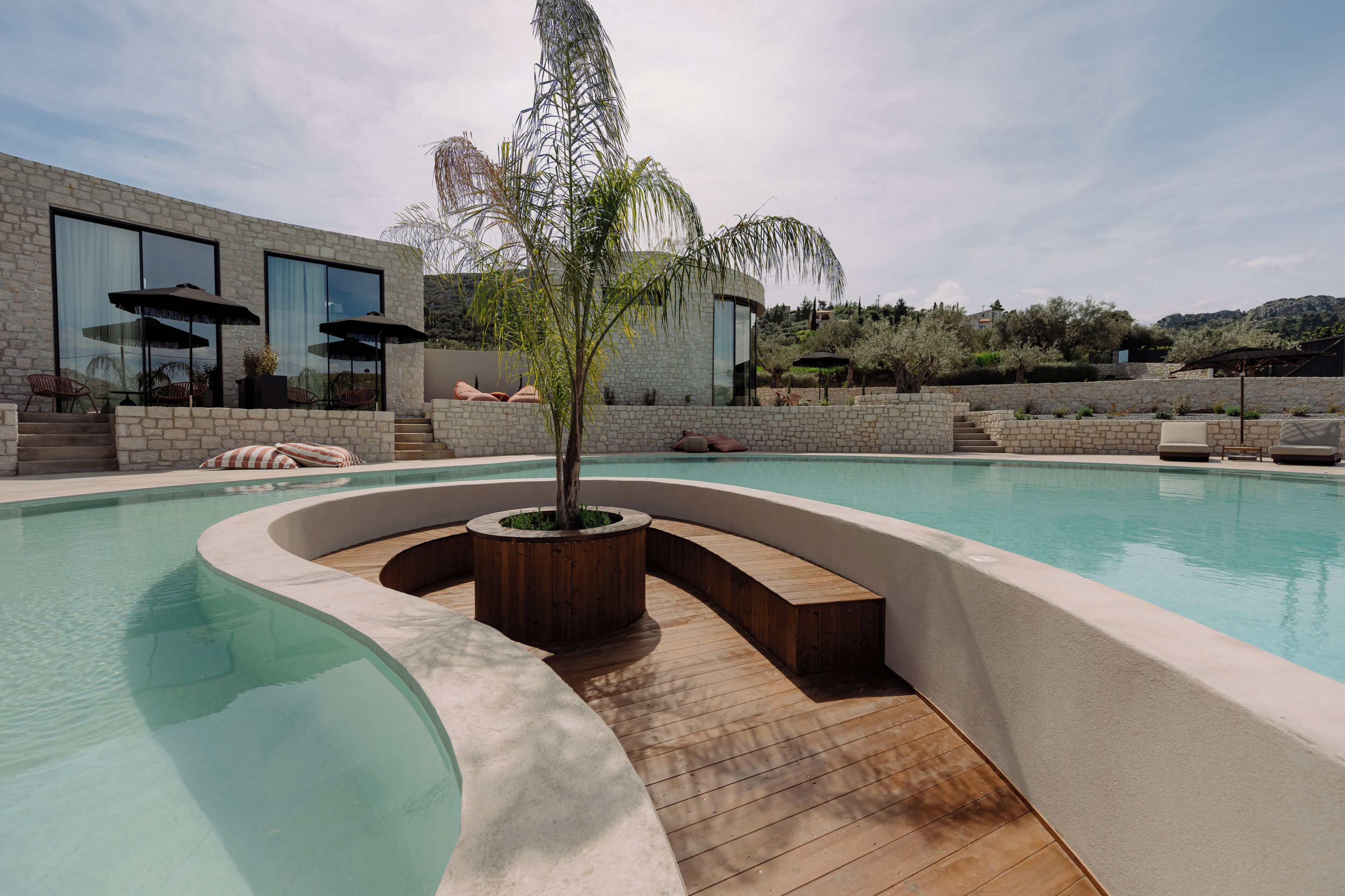 Uma área de piscina moderna com design curvo, um deck de madeira e uma grande janela com vista para a paisagem.