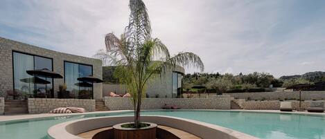 Uma área de piscina moderna com design curvo, um deck de madeira e uma grande janela com vista para a paisagem.