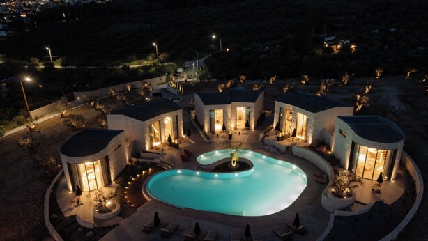 Un complexe hôtelier doté d’une piscine centrale, de plusieurs villas pour les clients et d’un éclairage extérieur.