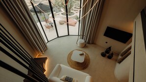 Un salon moderne avec un canapé blanc, une petite table ronde et un téléviseur à écran plat fixé au mur.